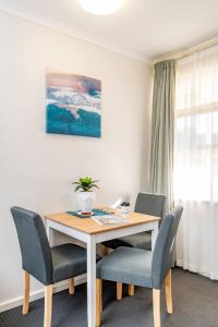 a dining room table with two chairs and a plant on it at Glenelg Central Studio Aqua in Glenelg