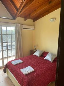 a bedroom with a red bed with towels on it at Cabañas del Duende El Volcan in El Volcán
