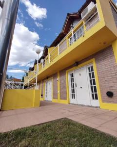 a yellow building with white doors and a balcony at Cabañas del Duende El Volcan in El Volcán