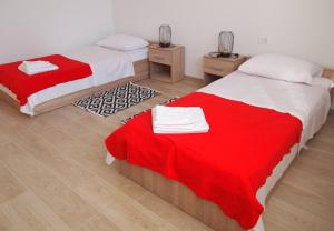 two beds in a room with red and white sheets at Apartment Nadalina in Kraljevica