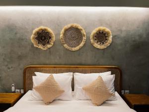 a bed with white pillows and three baskets on the wall at Griya tropical in Ubud