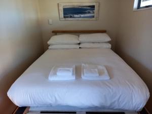 łóżko w pokoju z dwoma ręcznikami w obiekcie Raglan West Accommodation Units w mieście Raglan