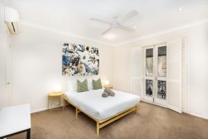 a white bedroom with a bed and two windows at Surry Hills Terrace in Sydney