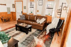 sala de estar con sofá de cuero marrón y mesa en Whitts Acres Cabin*RRG/Cave Run* en Big Woods