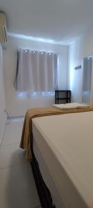 uma cama branca num quarto com uma janela em AP - Arretado em Campina Grande