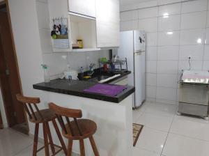 Casa da Bia apto 01 - apto inteiro في فيلا فيلها: مطبخ مع كرسيين بار وثلاجة