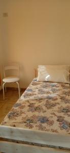 uma cama num quarto com uma cadeira ao lado em Villa Arcadia em Sierra de la Ventana