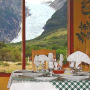 a table with plates and wine glasses and a view of the ocean at Monte Balmaceda Lodge & Glaciers in Torres del Paine