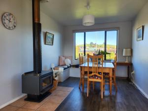 uma sala de jantar com um fogão a lenha, uma mesa e cadeiras em Mountainview em Kaikoura