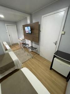 um quarto com uma cama e uma televisão de ecrã plano em Hospedar Flats & Residence em Santa Cruz do Sul