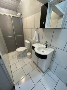 a white bathroom with a sink and a toilet at Hospedar Flats & Residence in Santa Cruz do Sul