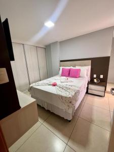 een slaapkamer met een groot bed met roze kussens bij Apartamento a beira-mar com piscina in Cabedelo