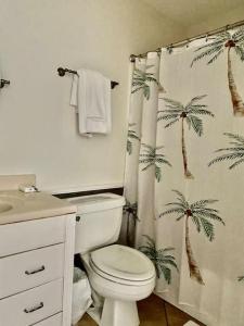 baño con aseo y cortina de ducha con palmeras en Tropical Lagoon on Betsy, en Panama City Beach