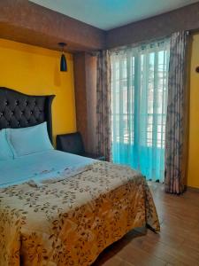 a bedroom with a bed and a large window at HOTEL LA BELLA Y EL LEON in Huánuco