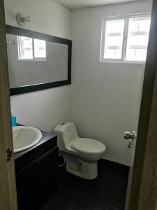 een badkamer met een toilet, een wastafel en een spiegel bij Casa la Alborada in Jamundí