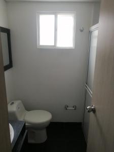 biała łazienka z toaletą i oknem w obiekcie Casa la Alborada w mieście Jamundí