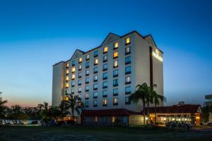 a hotel building with palm trees in the foreground at Fiesta Inn Tampico in Tampico