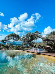 a pool of water with chairs and trees in the background at Casa Rosa - Terra Dourada, Paraíso na Natureza, piscina natural, Wi-Fi in Brasilia +38 photos