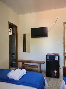 a room with a bed and a table and a television at Suítes Boa Viagem in Pirenópolis