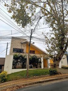 ein gelbes Gebäude mit einem Baum davor in der Unterkunft Casa Central Art Decor com Piscina e BBQ in Foz do Iguaçu