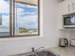 a kitchen with a sink and a window at Kingscliff Beachfront Abode - Hosted by Holiday Management in Kingscliff