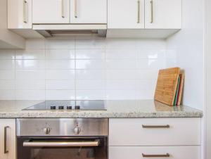 a kitchen with a stainless steel stove and white cabinets at Kingscliff Beachfront Abode - Hosted by Holiday Management in Kingscliff