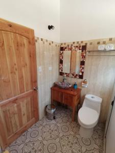a bathroom with a toilet and a wooden door at Samay Lodge in Cochiguaz