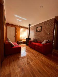 a living room with two red couches and a brick wall at 215 Cacique Catrini in Licán Ray