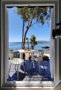 a table and chairs on a porch with a view of the ocean at La Pequeña Escandinavia, Havethus in Dichato