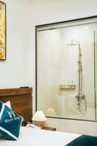 a glass shower in a bedroom with a bed at Milan Hotel Ninh Bình in Ninh Binh