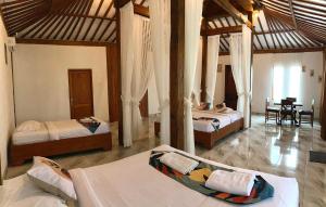 a bedroom with two beds and a table in it at Kampoeng Joglo Ijen in Banyuwangi