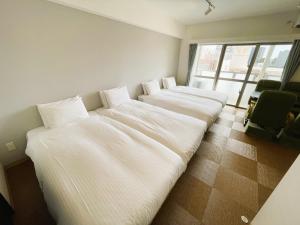 una fila di letti in una stanza con finestra di BiBi Hotel Cosmos Shintoshin a Naha