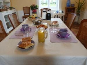a table with plates of food and glasses of orange juice at Château XIXe avec parc, chambres spacieuses et petit déjeuner local, proche forêt et cité médiévale - FR-1-410-411 in Parennes