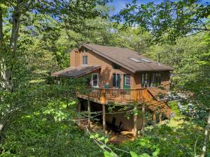 a house with a deck in the woods at Serene & Fun Family Gem ~ Big Bass Lake Community! in Gouldsboro