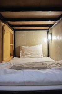 a bed with a white pillow on top of it at Cazz Hostel in Bangkok