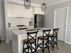 a kitchen with a white counter and four bar stools at 21 On Court in Mudgee