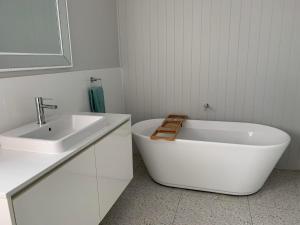 a white bathroom with a sink and a bath tub at 21 On Court in Mudgee