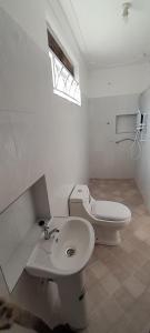 a white bathroom with a sink and a toilet at Maasai Villa Backpackers Home in Fort Portal
