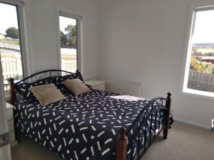 a bedroom with a bed and two windows at Self contained guest suite in Oatlands