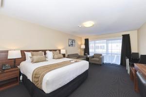 ロトルアにあるNewina Rotoruaの大きなベッドとデスクが備わるホテルルームです。