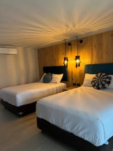 duas camas num quarto de hotel com lençóis brancos em GUAJIRA CASA DEL MAR em Ríohacha