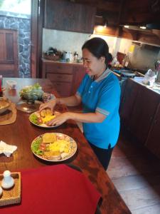 una mujer parada en una cocina con un plato de comida en WOODEN HOUSE CANDIDASA en Manggis