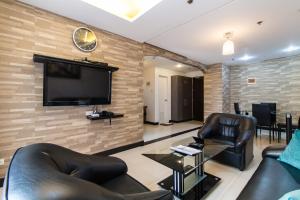 uma sala de estar com mobiliário de couro e uma televisão de ecrã plano em Pacific Bay Grand Suites em Manila