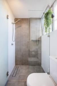 a bathroom with a shower with a toilet and a sink at 'Aquarius Rising' Poolside in Rushcutters Bay in Sydney
