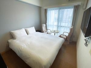 una camera da letto con un grande letto bianco e una finestra di BiBi Hotel Cosmos Shintoshin a Naha