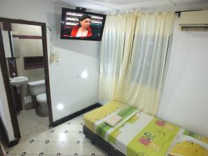 een kleine kamer met een bed en een tv aan de muur bij Hotel malecón del Rio in Barranquilla