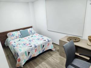 a bedroom with a bed and a desk and a chair at Lugar perfecto para ti a solo 300 metros de la playa in Gaira
