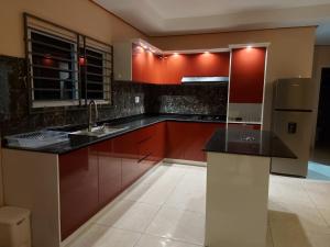 a kitchen with red cabinets and a refrigerator at A&N appartementen in Lelydorp