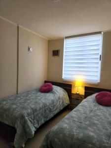 1 dormitorio con 2 camas con almohadas rojas y ventana en Condominio privado. Cómodo y central departamento nuevo en Talca