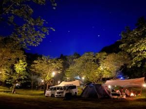 a group of tents and vehicles parked at night at ぼっちの森 in Minamiizu